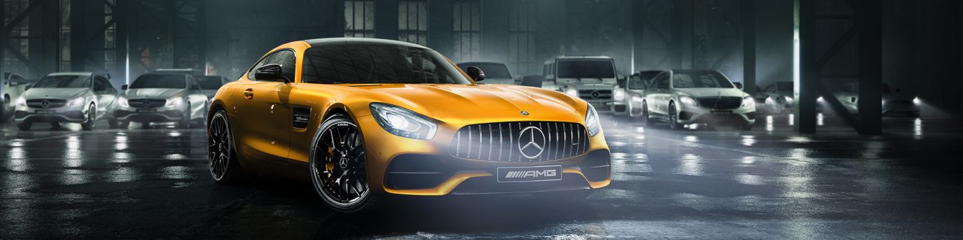 L'immagine mostra l'affascinante AMG GT con vernice gialla davanti alla gamma delle vetture performance AMG.